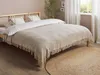 A bedroom scene with a bed made up with a light-colored blanket and pillows. Podgląd zdjęcia produktu