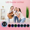 A family is singing karaoke in a living room, with a portable speaker and colorful lights in the foreground. Produktbild-Vorschau