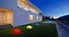 A modern house with a swimming pool and garden at dusk, featuring illuminated decorative stones on the lawn. Produktbild-Vorschau