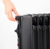 A hand is shown adjusting a knob on a black electric heater. Podgląd zdjęcia produktu