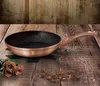 A rose gold frying pan with a black interior sits on a wooden table, with roses and chocolate chips scattered around. Voir les images du produit