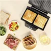 A sandwich maker with two sandwiches inside, surrounded by ingredients for making sandwiches, and a glass of water. Podgląd zdjęcia produktu