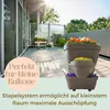 A balcony with wooden decking and a stacked planter system filled with flowers. Produktbild-Vorschau
