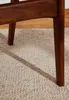 Close-up of the legs of a wooden chair resting on a cream-colored rug. Voir les images du produit