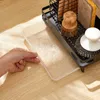 A hand is shown placing a clear plastic drip tray under a black metal dish rack on a wooden surface. Voir les images du produit