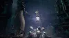 A character in a long coat stands in a graveyard at night, reaching towards several small, skeletal figures gathered around a lantern. Náhled obrázku produktu