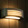 A modern outdoor wall lamp mounted on a dark wooden wall. Anteprima dell’immagine prodotto