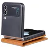 A black flip phone case is open and resting on a brown leather wallet. The phone screen displays the time and date. Produktbild-Vorschau