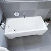 A white bathtub in a modern bathroom with gray tiled walls and floor. Produktbild-Vorschau