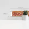 A decorative border with a floral pattern is shown on a wall, with measurement indicators. A potted plant is placed next to it. Podgląd zdjęcia produktu