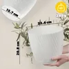 A person holding a white planter with dimensions indicated by lines and text. Produktbild-Vorschau