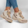 A pair of beige Skechers women's sneakers worn by a person. Podgląd zdjęcia produktu