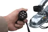 A hand holding a trailer connector plug near a trailer hitch. Produktbild-Vorschau