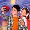 Two children are taking a selfie with a red toy camera in front of a Ferris wheel. Voir les images du produit