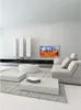 A modern living room with a sofa, coffee tables, and a TV mounted on the wall. Produktbild-Vorschau
