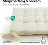A close-up of a cream-colored tufted cushion with ties, featuring various certifications and descriptive text. Náhled obrázku produktu