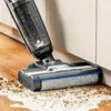 A vacuum cleaner is cleaning up a mess on a wooden floor next to a wall. Voir les images du produit