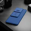 A blue phone case with a sliding camera cover is placed on a dark gray surface. Produktbild-Vorschau
