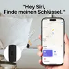 A hand holding a smartphone displaying a map application, with a small black device partially visible under a white pillow. The scene suggests the device is being located using the phone. Náhled obrázku produktu