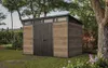 A modern garden shed with a wood-like finish is situated in a lush garden setting. Náhľad obrázku produktu