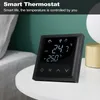 A black smart thermostat is placed on a white table next to a lamp and a bed. Podgląd zdjęcia produktu