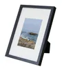 A black picture frame with a white mat and a picture of a sailboat on the ocean. Produktbild-Vorschau