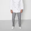 A person wearing a chef's uniform and checkered pants, standing against a plain background. Produktbild-Vorschau