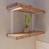 Two wooden shelves mounted on a wall with white brackets. A small potted plant is on the lower shelf. Produktbild-Vorschau