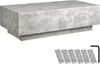 A rectangular coffee table with a concrete-like finish, shown from a slightly elevated side angle. Below the table are several small rectangular items and an L-shaped tool.