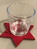 A clear glass votive holder with a snowflake design sits on a red star-shaped felt coaster. Produktbild-Vorschau
