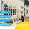 A woman is standing on a patio next to a sofa, gesturing towards a house with a retractable awning. Náhled obrázku produktu