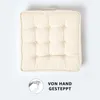 A square, tufted cushion with a loop handle on top, presented on a white background. Produktbild-Vorschau
