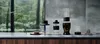 A collection of blender components and accessories are displayed on a countertop in front of a window with a forest view. Podgląd zdjęcia produktu