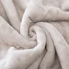 A close-up view of a soft, beige blanket folded into a swirl. Podgląd zdjęcia produktu