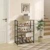 A shoe rack filled with shoes, placed in a hallway next to a door and stairs. Náhľad obrázku produktu