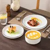 A table setting with plates of food, a glass of water, and a salt and pepper grinder. Voir les images du produit