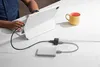 A person is using a tablet connected to a hub and external storage device, with a mug nearby. Voir les images du produit