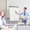 A business presentation with a man pointing at a flip chart to two colleagues. Produktbild-Vorschau