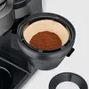 A close-up view of a coffee filter filled with ground coffee in a coffee maker. Produktbild-Vorschau
