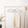 A minimalist display of clothing hangers and a beige slip dress on a wooden garment rack. Náhled obrázku produktu