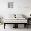 A minimalist bedroom scene featuring a black metal bed frame with white bedding and pillows, a framed abstract artwork on the wall, and a bedside table with a lamp. Voir les images du produit