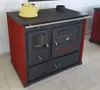 A red and black wood-burning stove with a yellow kettle on top, placed indoors on a tiled floor. Náhled obrázku produktu