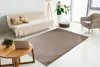 A living room scene with a sofa, armchair, coffee table, and a rug. Produktbild-Vorschau