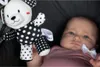 A baby is looking at a black and white teddy bear toy. Anteprima dell’immagine prodotto