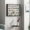 A wall-mounted display cabinet filled with rocks and minerals, placed on a white wall next to a framed picture of the ocean. Podgląd zdjęcia produktu