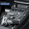 A portable car vacuum cleaner is placed on the center console of a car, next to the gear shifter and cup holders. The car's interior features carbon fiber accents. Produktbild-Vorschau