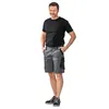 A man wearing a black t-shirt and gray cargo shorts stands against a white background. Produktbild-Vorschau