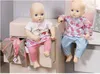 Two baby dolls sitting on the edge of drawers, with a travel bag next to one. Podgląd zdjęcia produktu