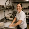 A woman is washing dishes in a commercial kitchen sink. Produktbild-Vorschau
