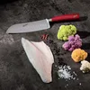 A Santoku knife with a red handle is placed on a dark surface next to a raw fish fillet and several colorful cauliflower florets. Produktbild-Vorschau